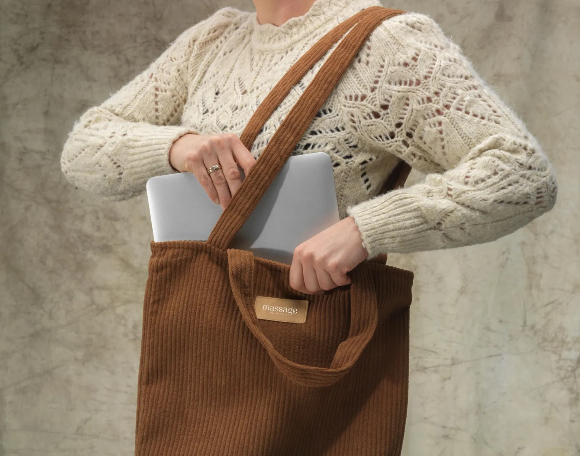 Sacoche ordinateur en velours côtelé marron, portée à l'épaule avec un ordinateur portable