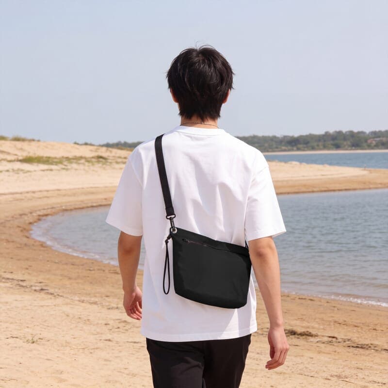 Sac bandoulière noir porté sur une plage