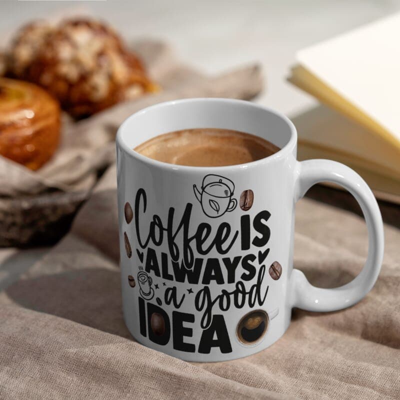 Mug imprimé tout autour posé sur une table de petit-déjeuner, avec viennoiseries