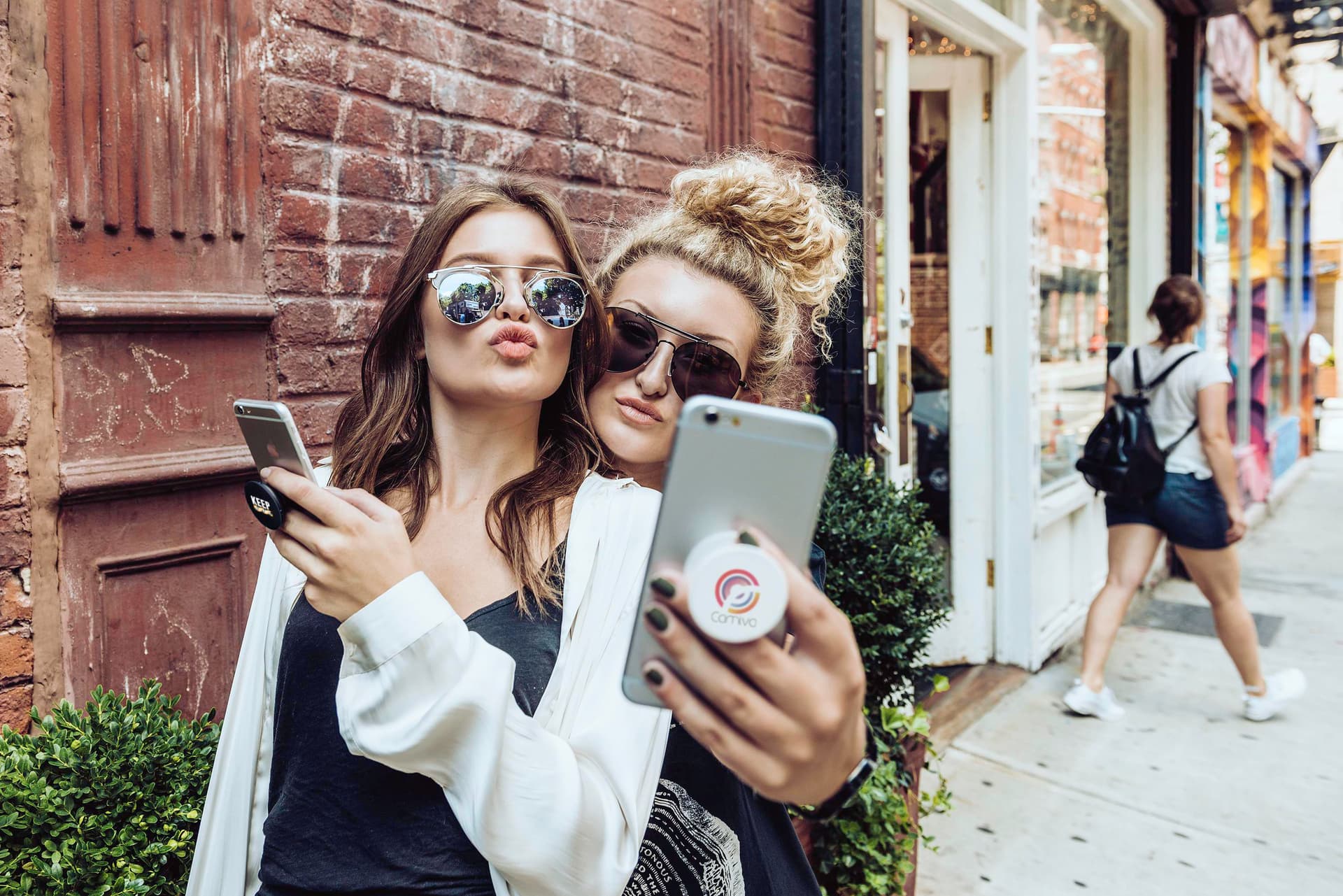 Deux amies se prennent en photo, un support de téléphone au dos du smartphone