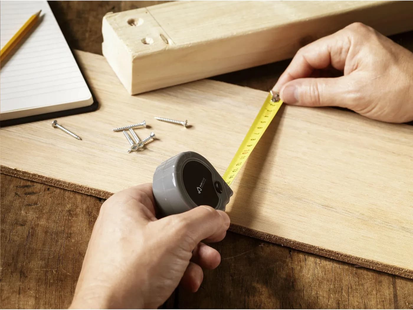 Mains utilisant un mètre-ruban sur une planche de bois